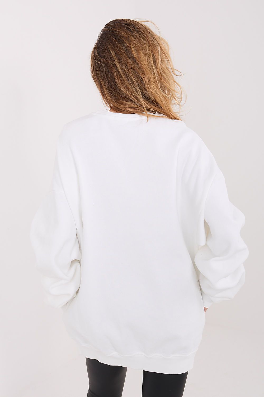 Person wearing a white oversized sweater on a plain background