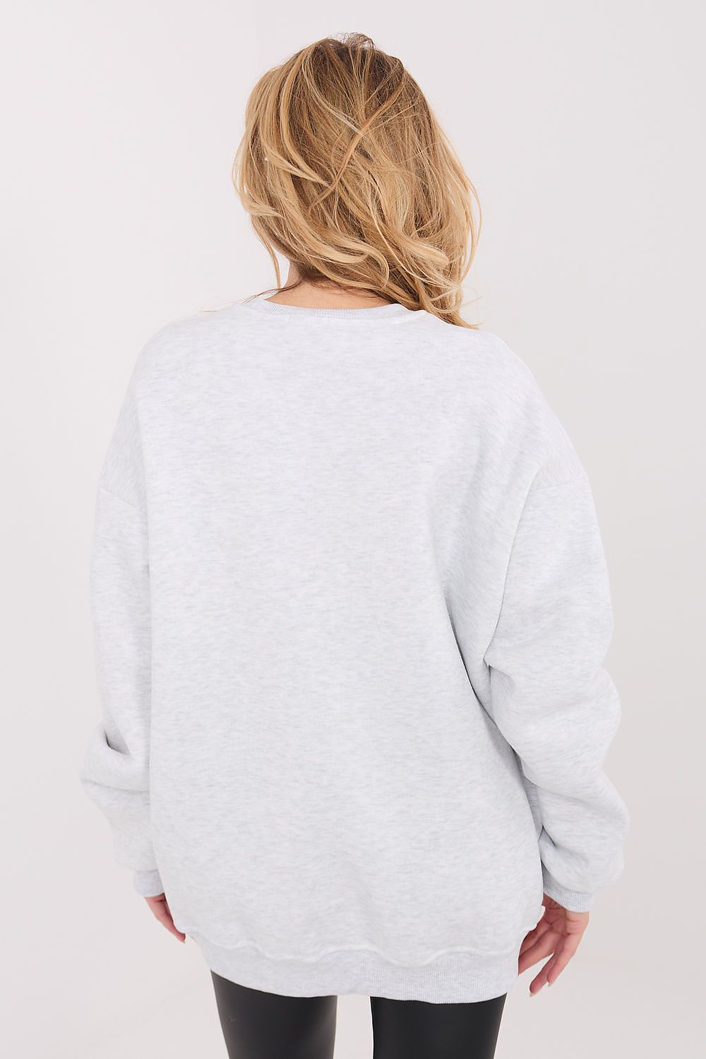 Person wearing a light gray sweatshirt with a plain background