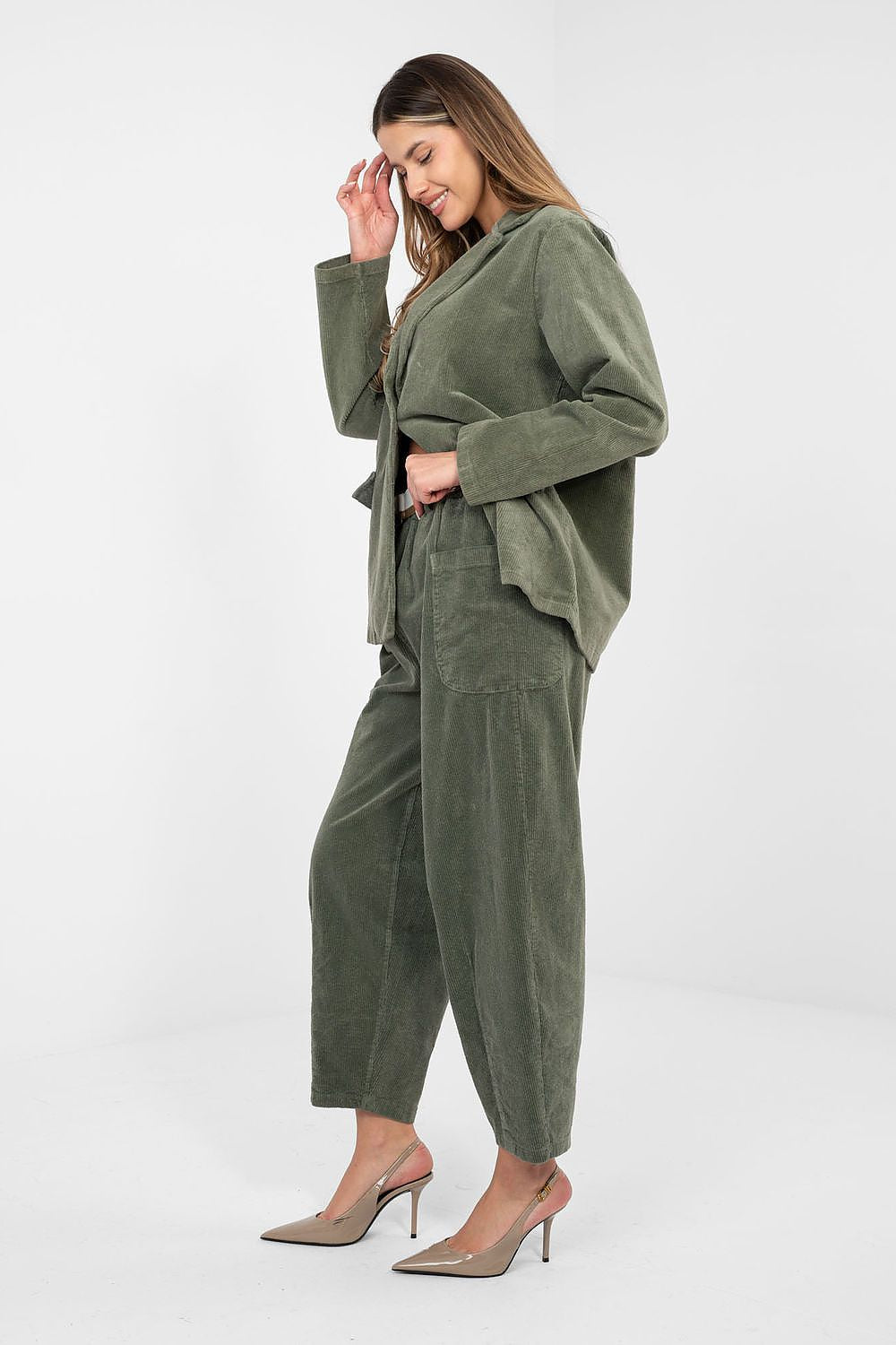 Woman wearing a green corduroy outfit on a white background