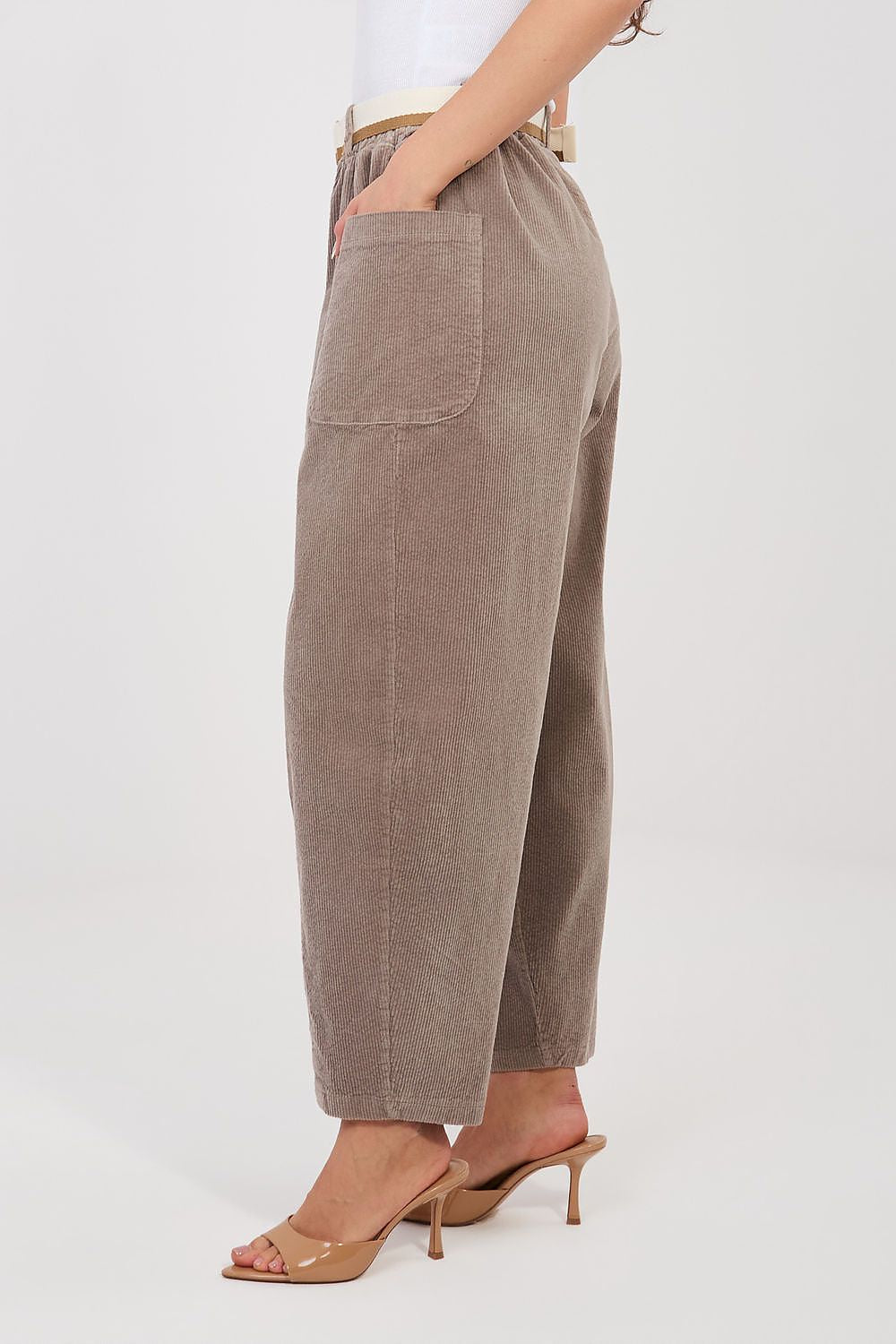 Brown corduroy pants worn by a person on a white background