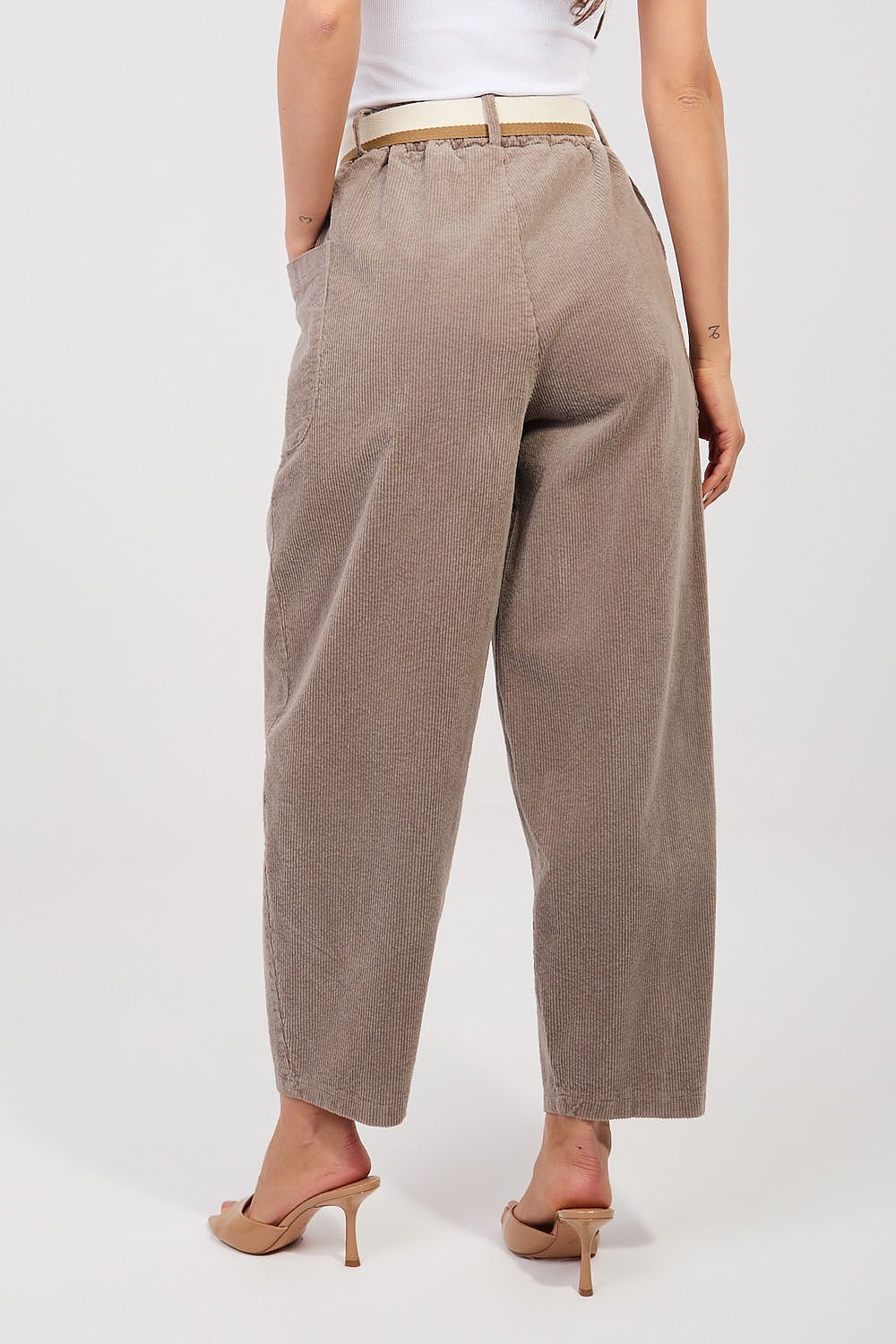 Person wearing beige wide-leg pants on a white background