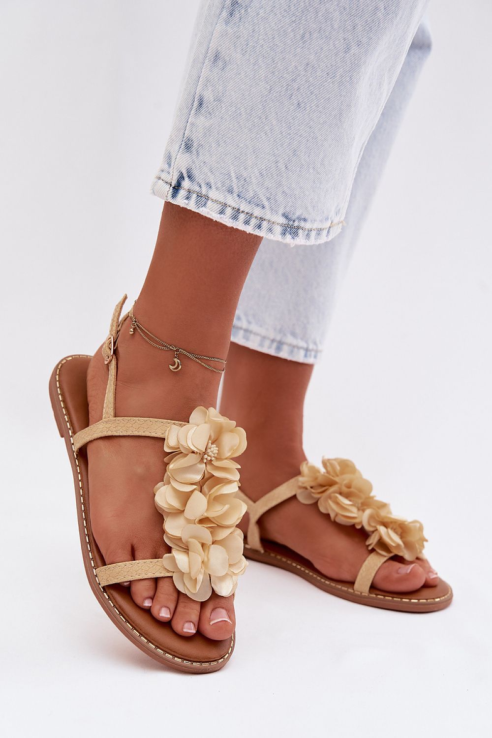Beige sandals with floral decorations on a white background