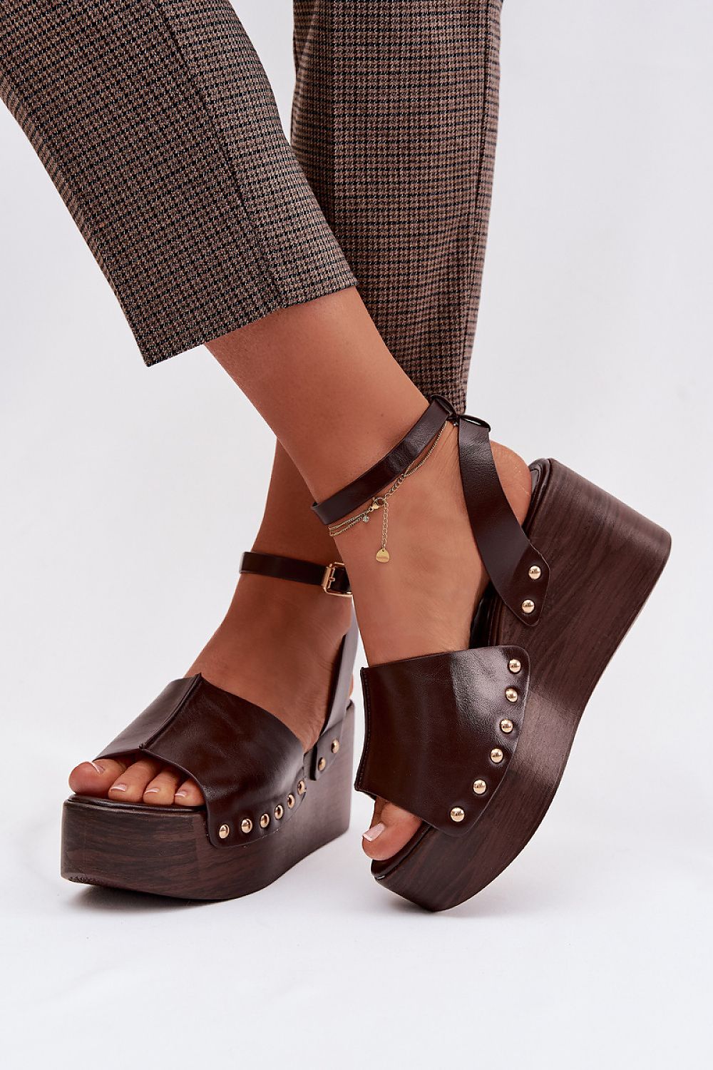 Brown platform sandals worn with plaid pants on a white background