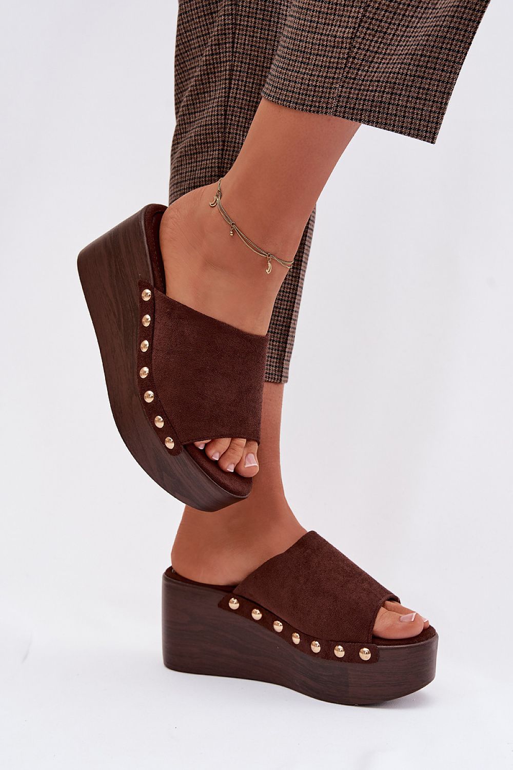Brown platform sandals worn with plaid pants on a white background