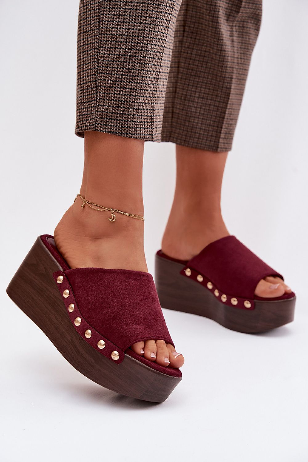 Burgundy platform sandals with wooden sole worn by a person on a white background
