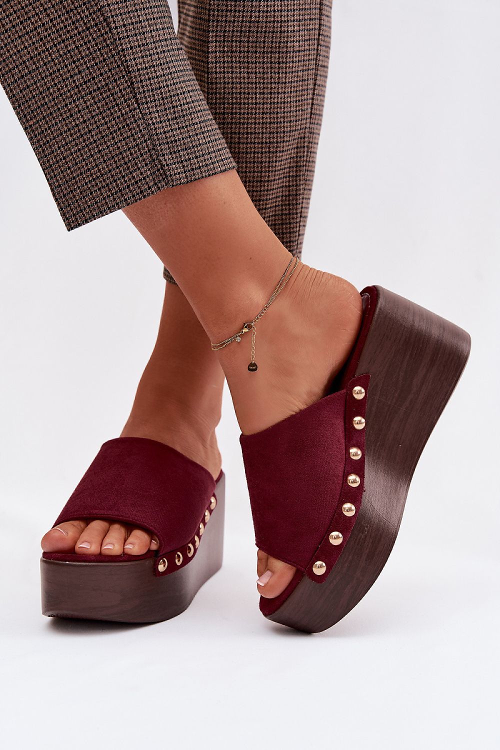 Burgundy platform sandals with wooden sole worn by a person on a white background