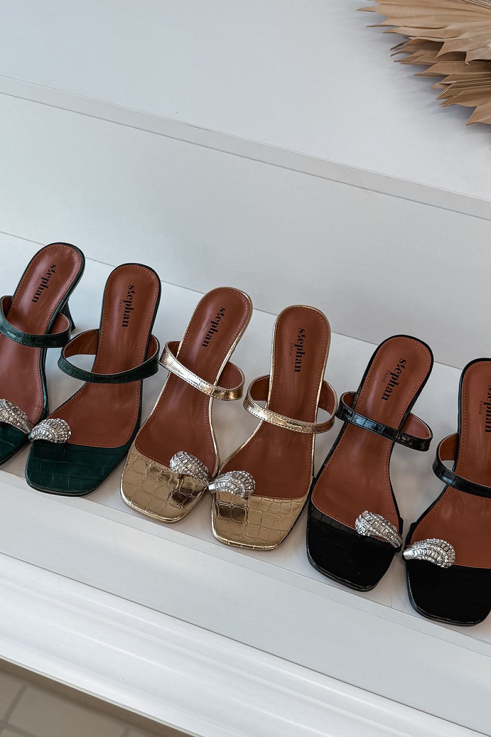 Set of women's sandals in various colors with decorative straps on a white surface.