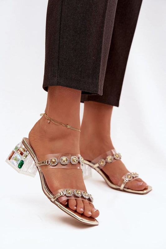 Clear high-heeled sandals with gemstone embellishments on a white background