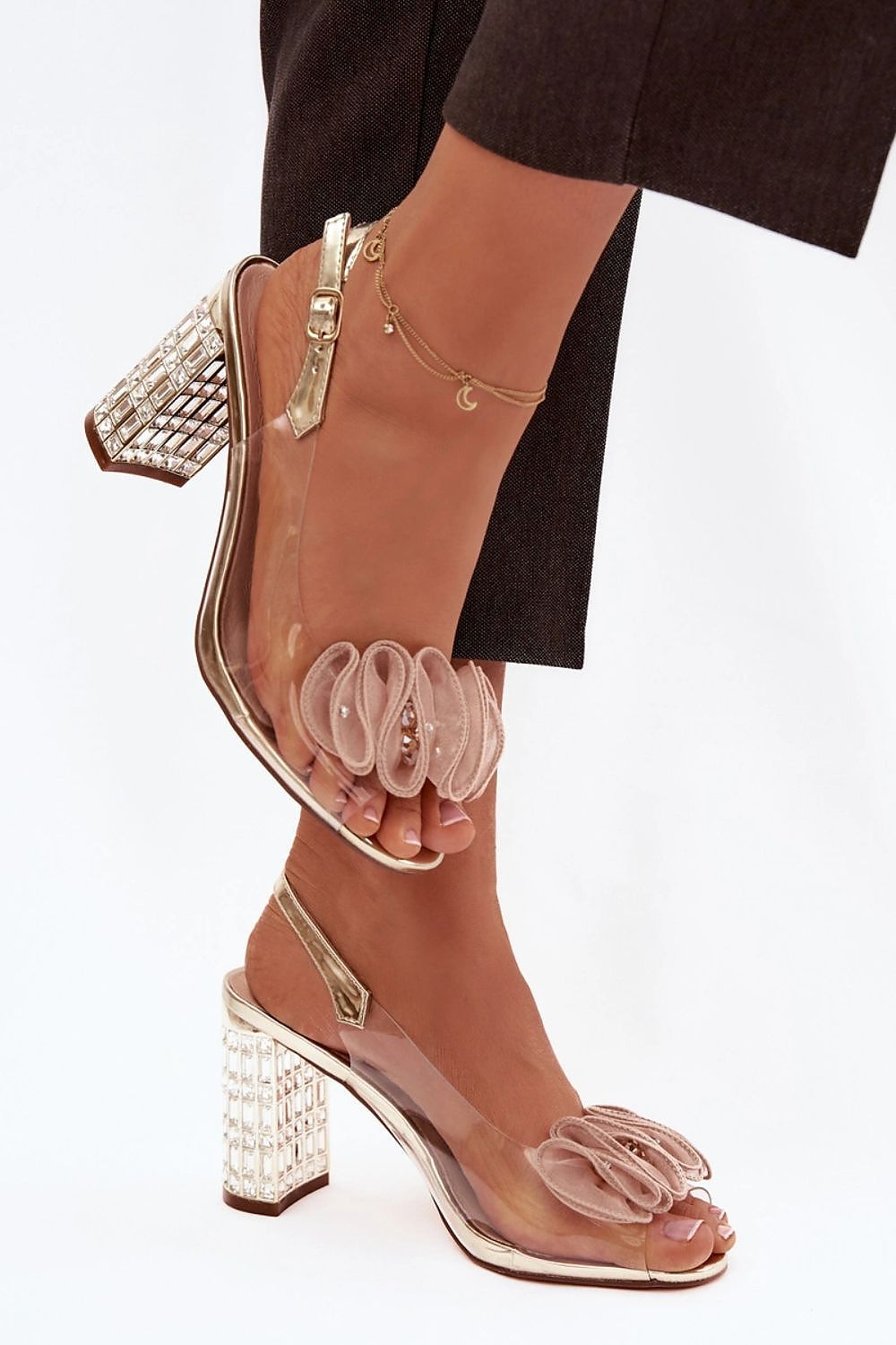 Clear high-heeled shoes with decorative elements on a white background