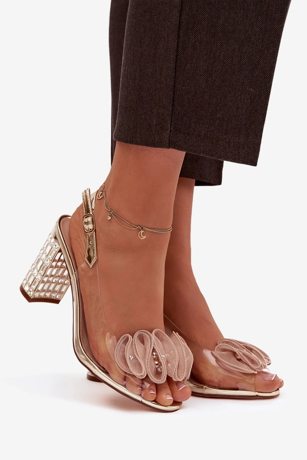 Clear high-heeled shoes with embellishments on a white background