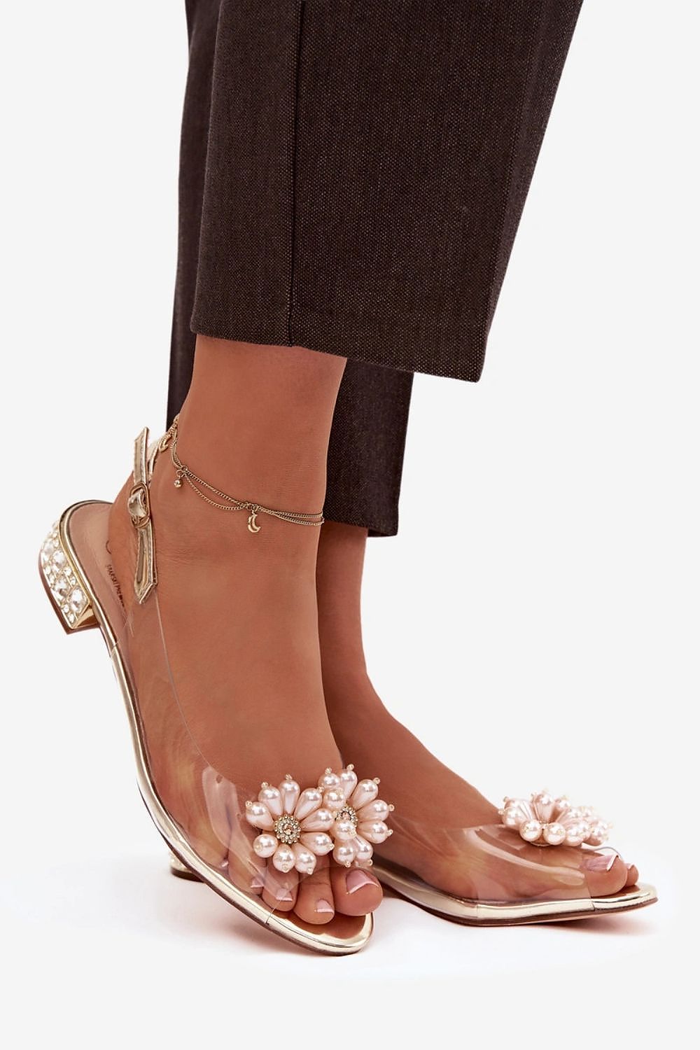 Transparent sandal with floral embellishments on a white background