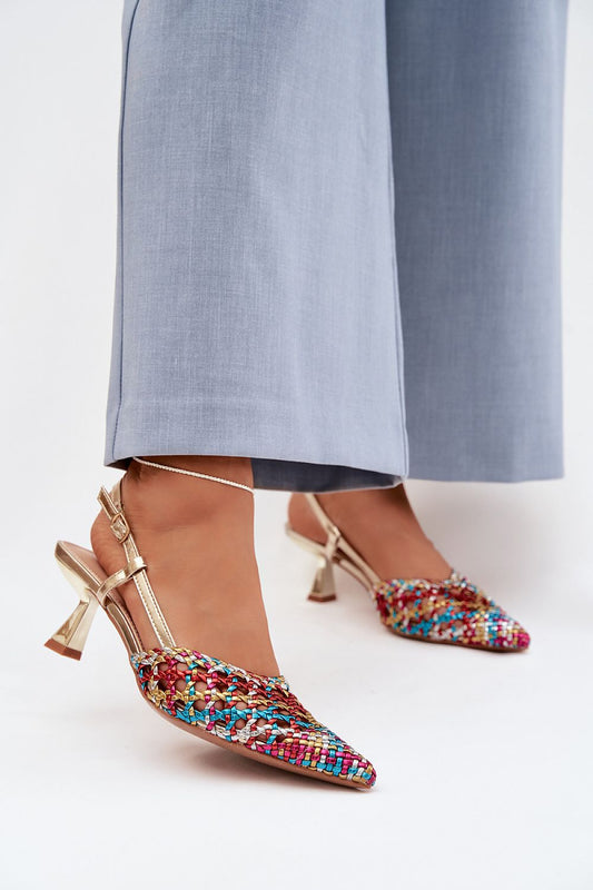 Multicolored embellished shoes worn with light blue pants on a white background