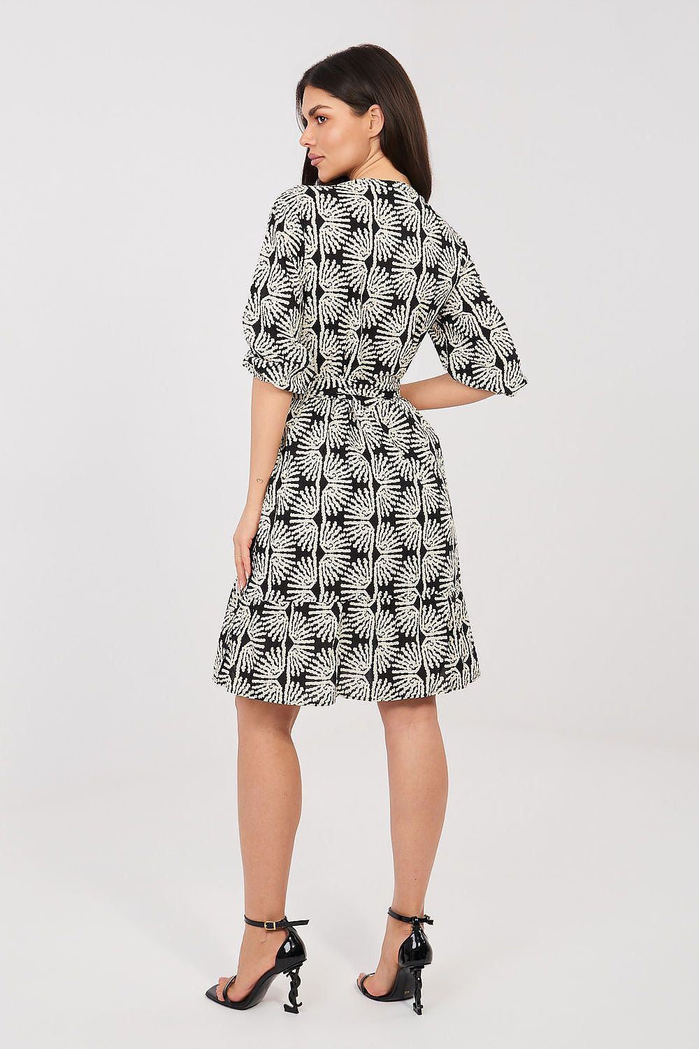 Woman wearing a black and white patterned dress on a white background