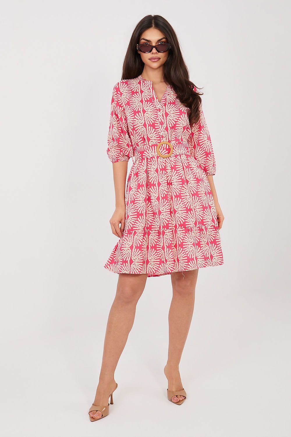 Woman wearing a pink and white patterned dress on a white background