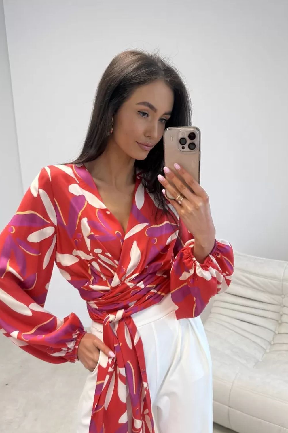 Woman taking a mirror selfie wearing a red floral dress.