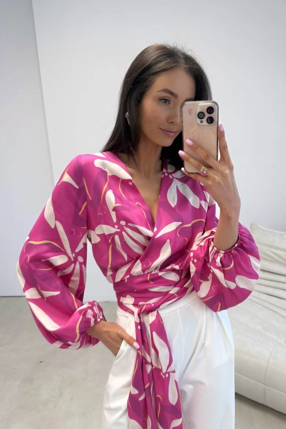 Woman taking a mirror selfie wearing a pink and white patterned dress.