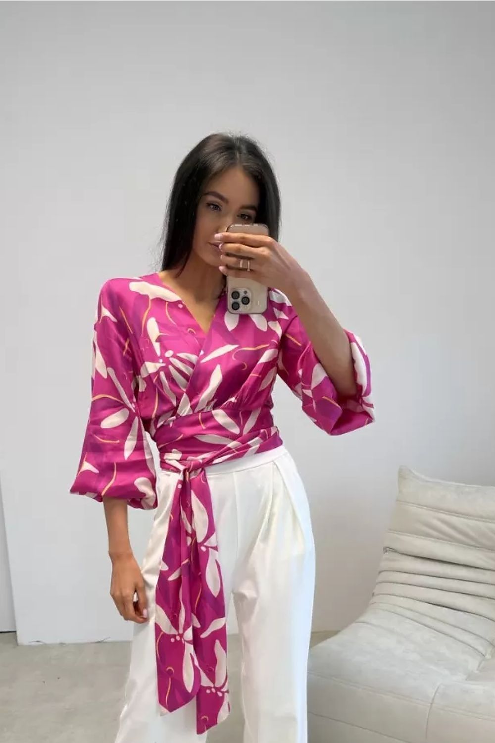 Woman taking a mirror selfie wearing a pink and white floral dress.