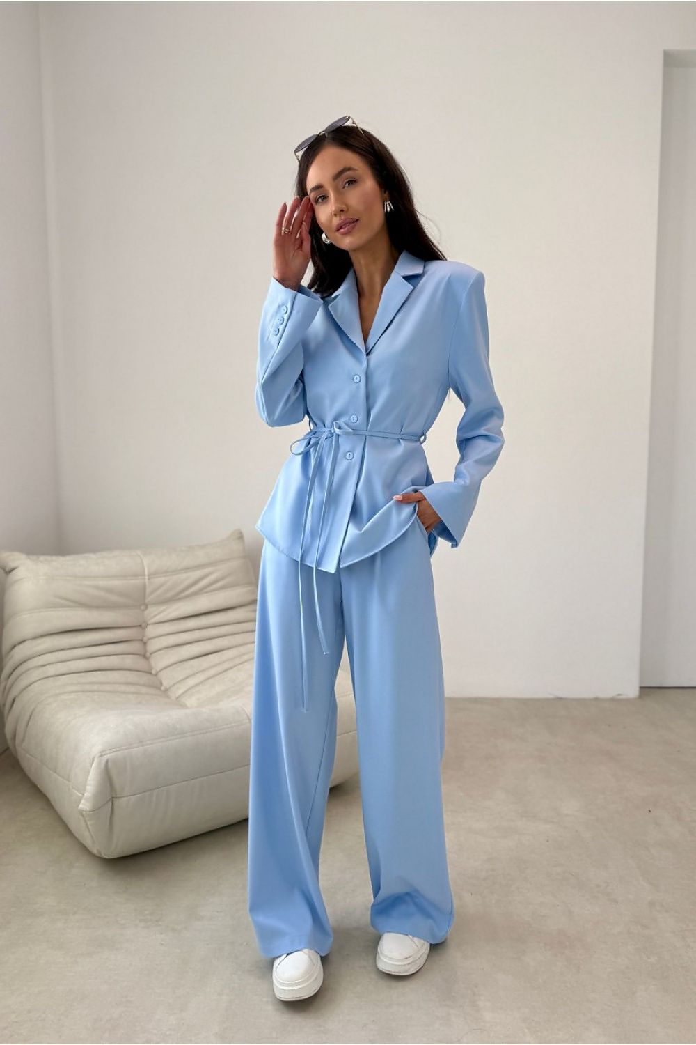 Woman wearing a light blue suit in a minimalistic room.