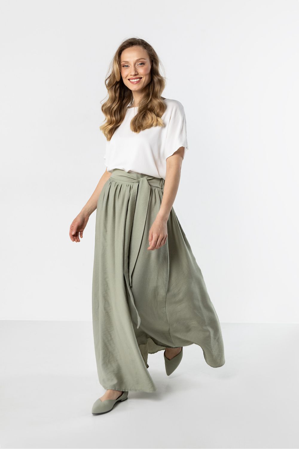 Woman wearing a white top and green skirt on a white background