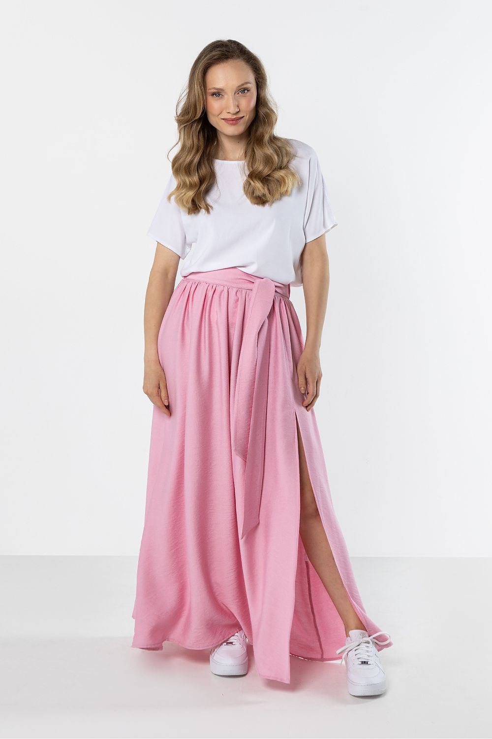 Woman wearing a white t-shirt and pink skirt on a white background