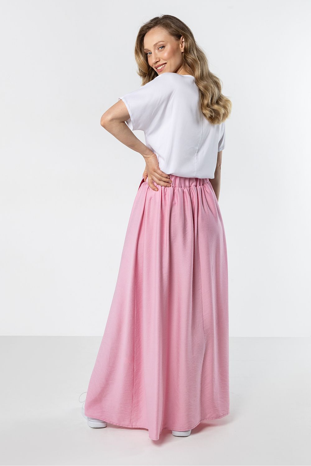 Woman wearing a white top and pink skirt on a white background