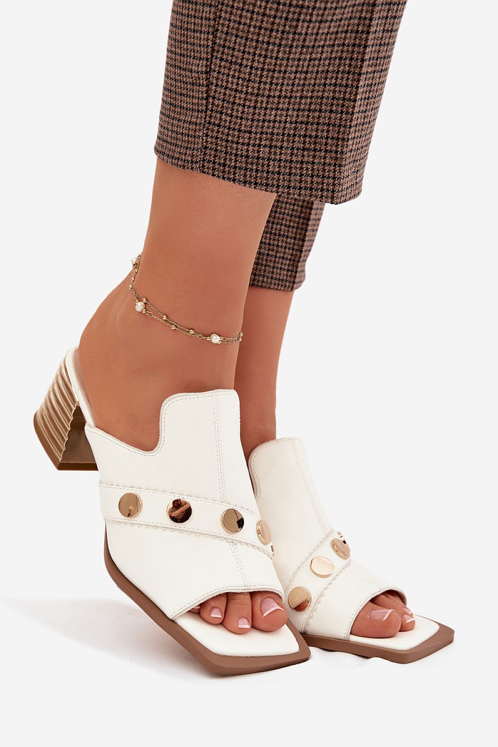 White sandals with brown accents worn by a person on a white background