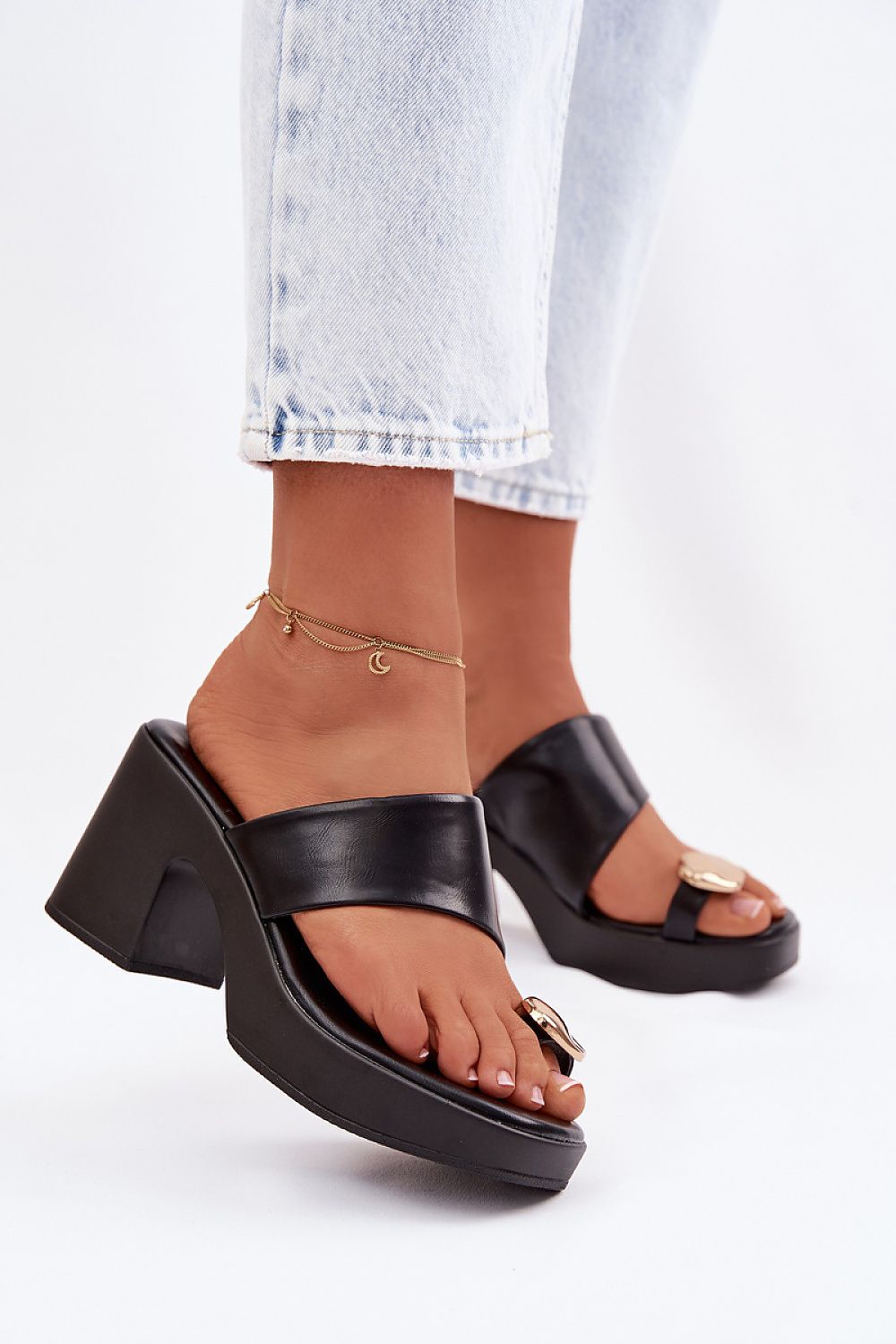 Black platform sandals worn with light blue jeans on a white background