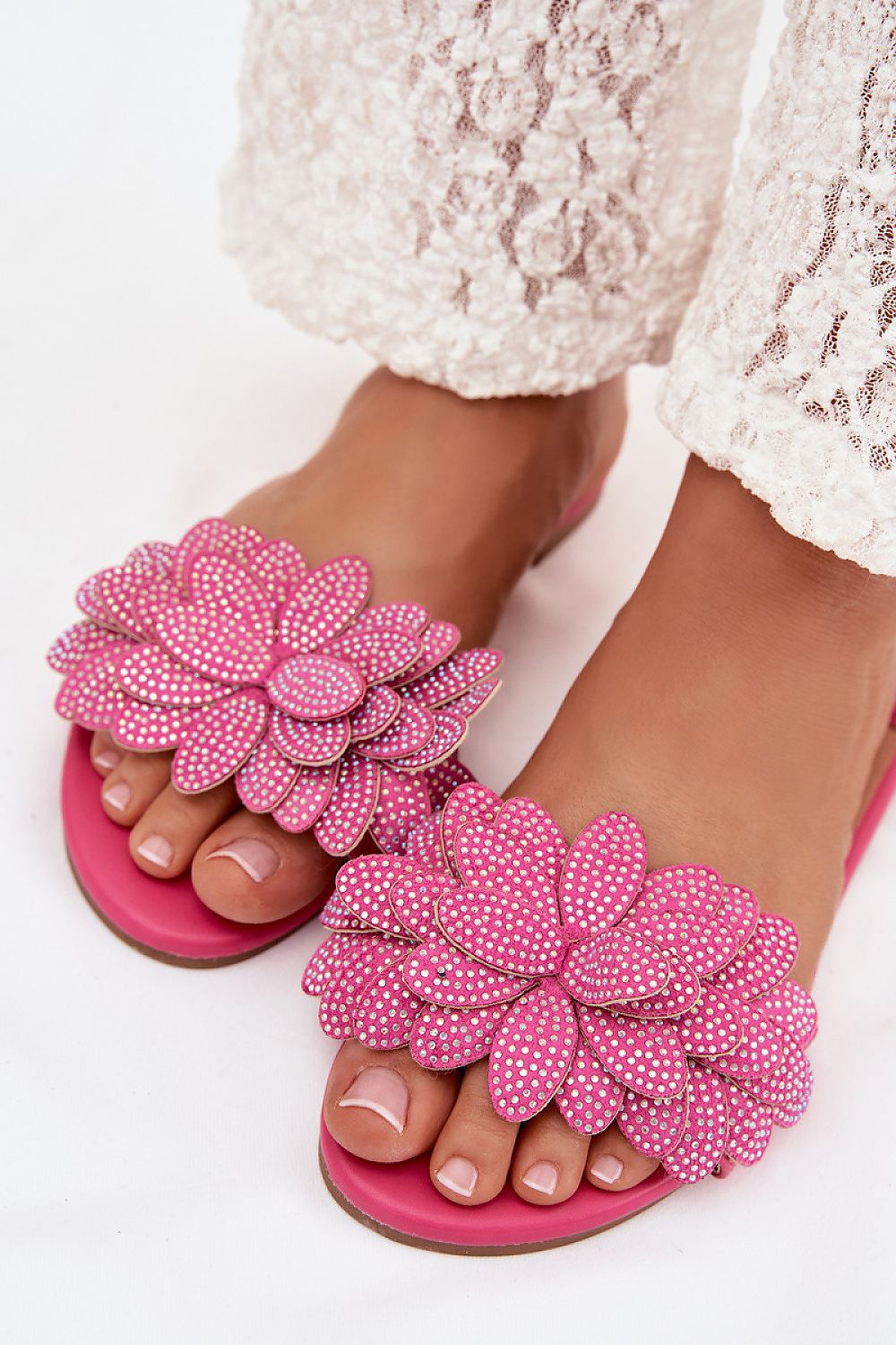 Pink floral sandals with white polka dots worn by a person on a white background