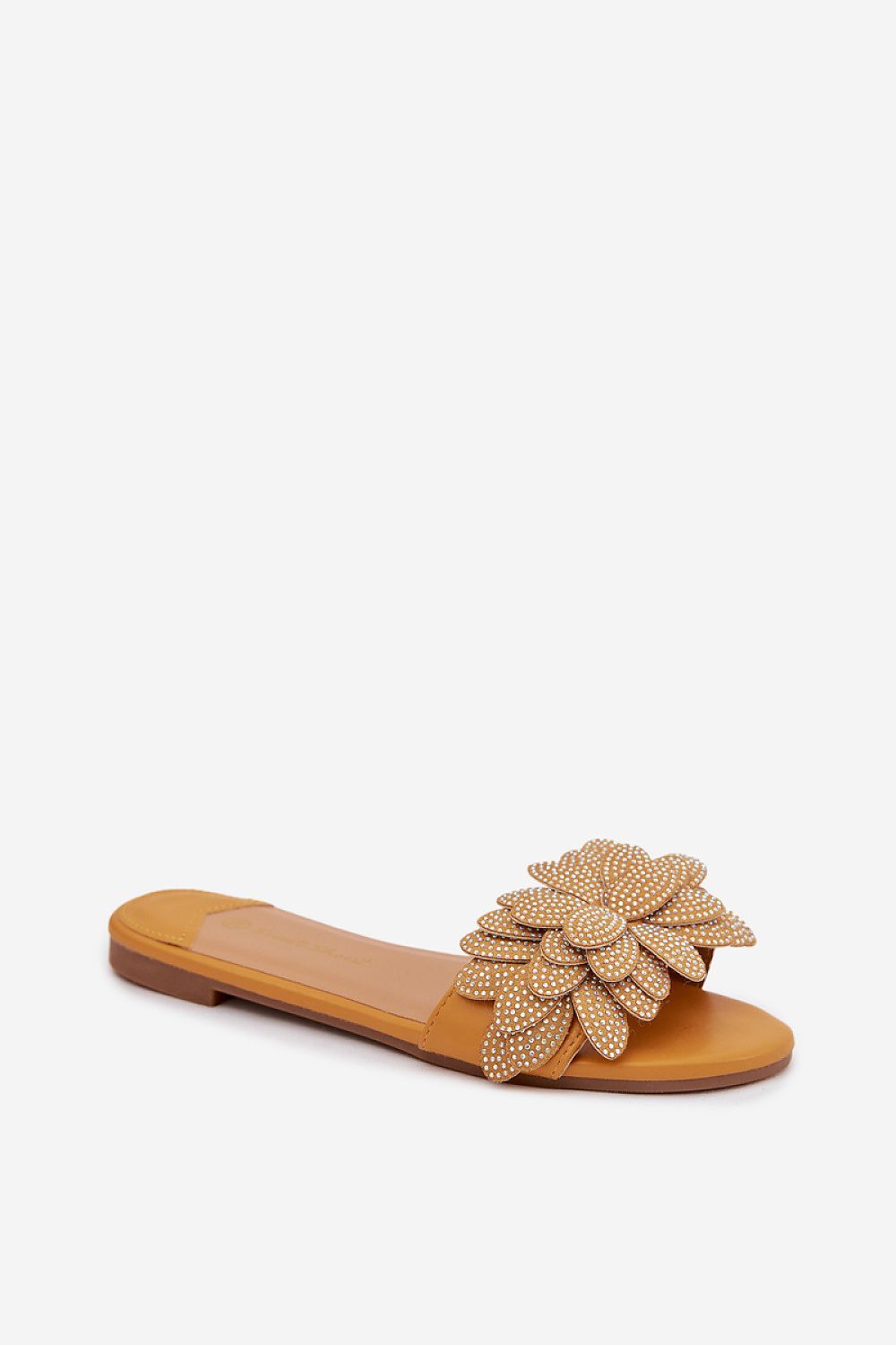 Tan sandal with a decorative flower embellishment on a white background