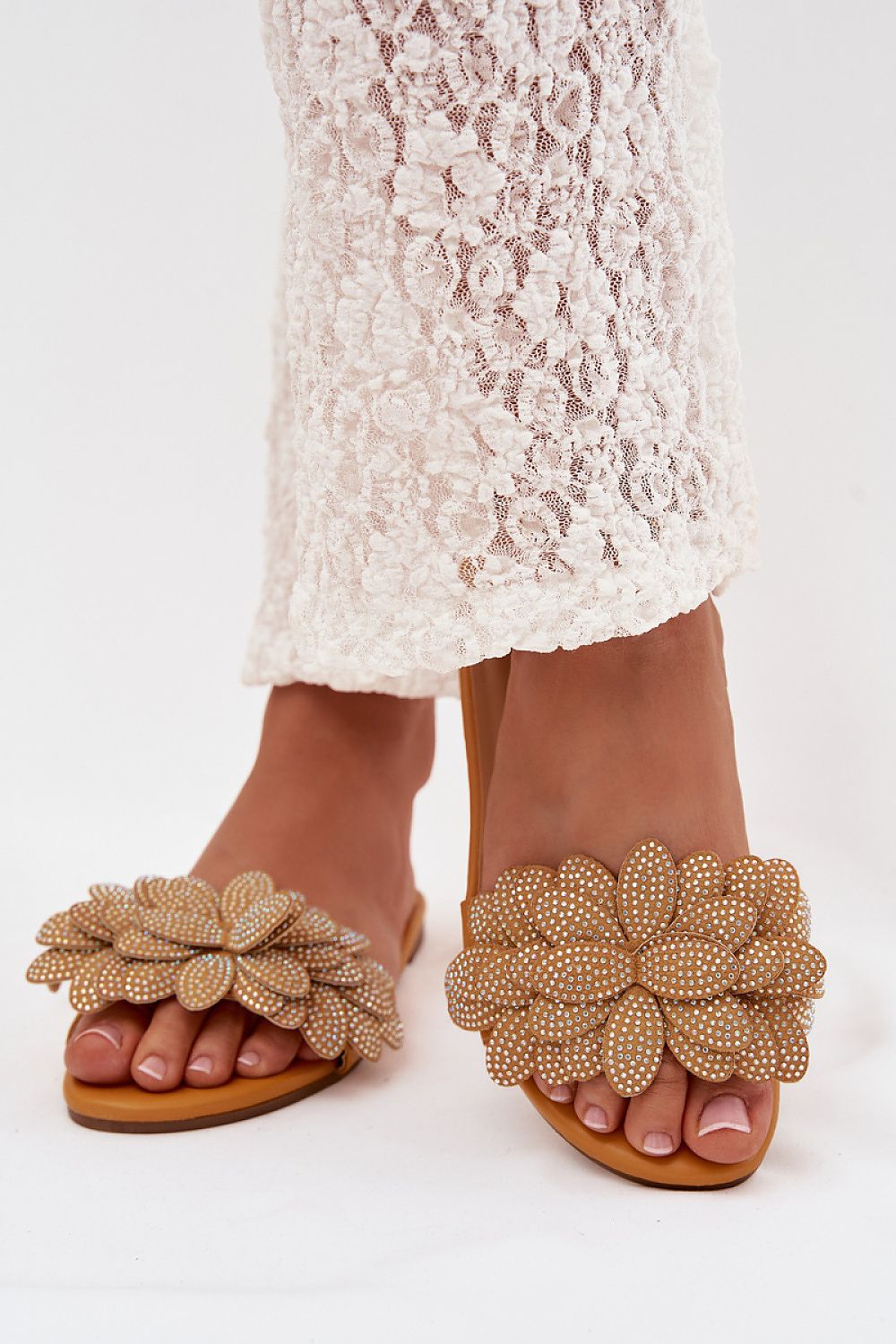 Beaded flower sandals worn with a lace dress on a white background