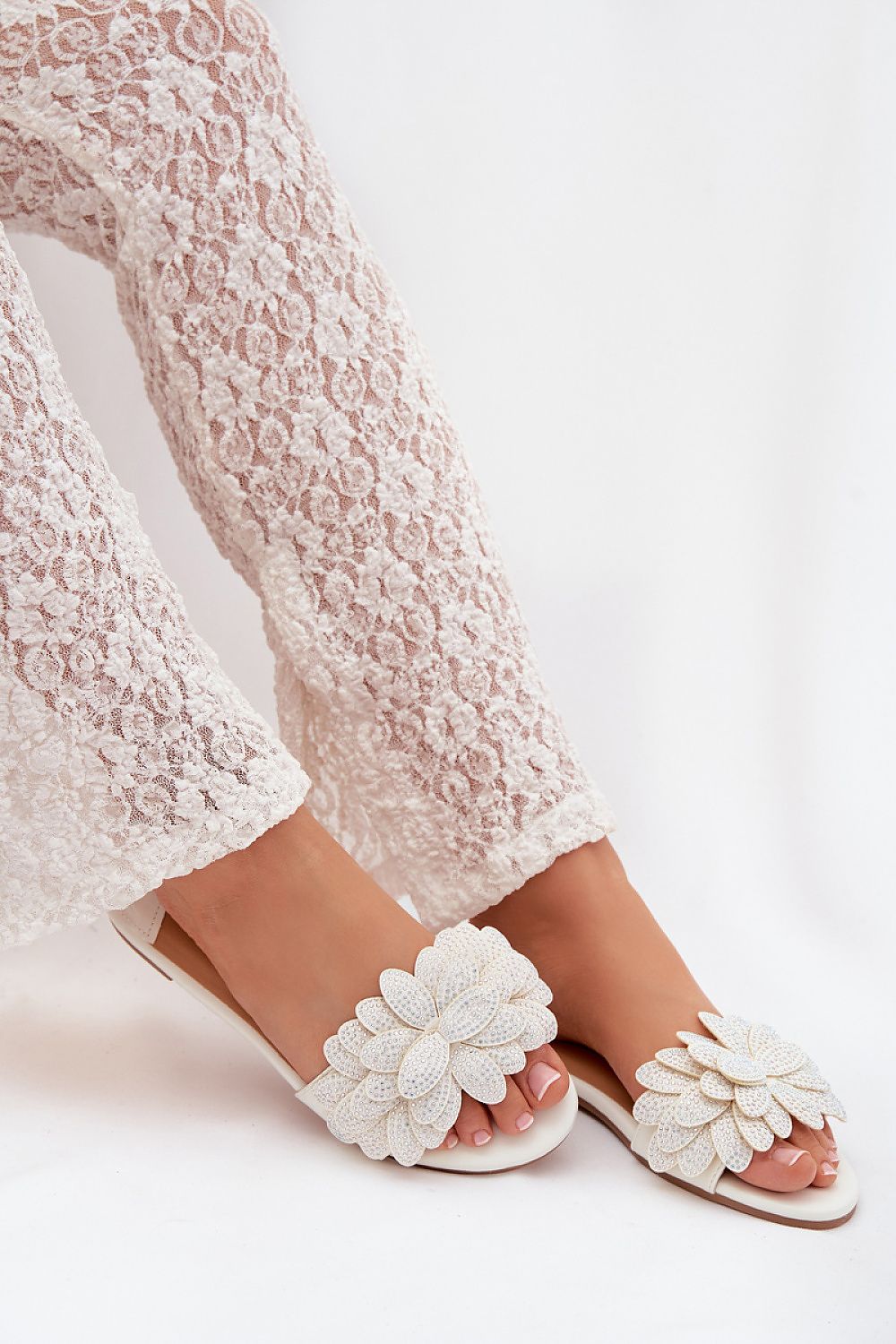 White lace pants with white floral sandals on a white background