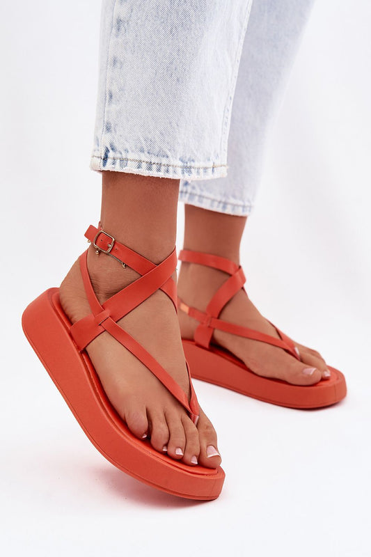 Orange sandals worn with light blue jeans on a white background