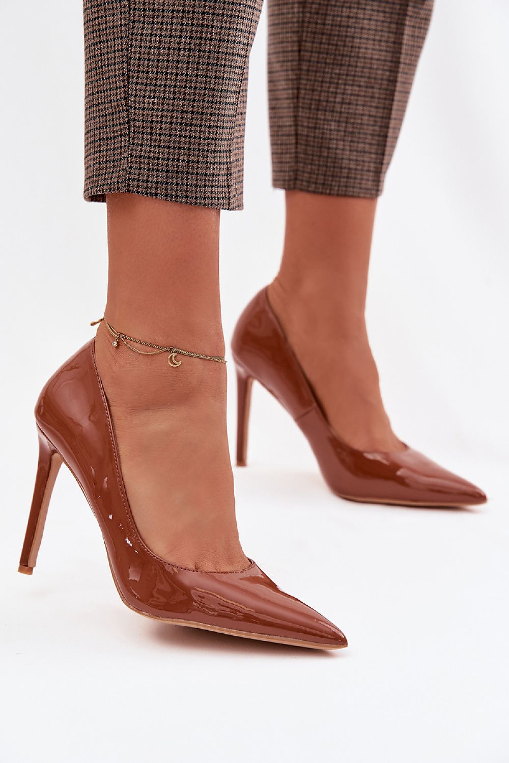 Brown high-heeled shoes worn with plaid pants on a white background