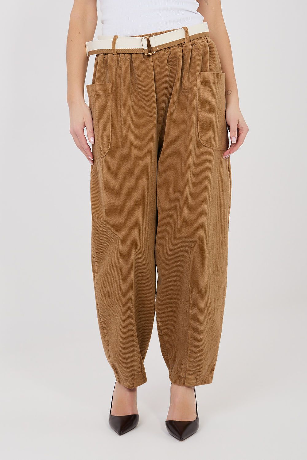 Brown corduroy pants worn by a person on a white background