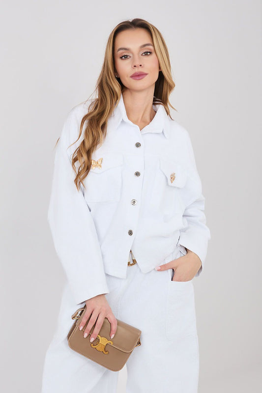 Woman wearing a white outfit with a beige handbag on a plain background