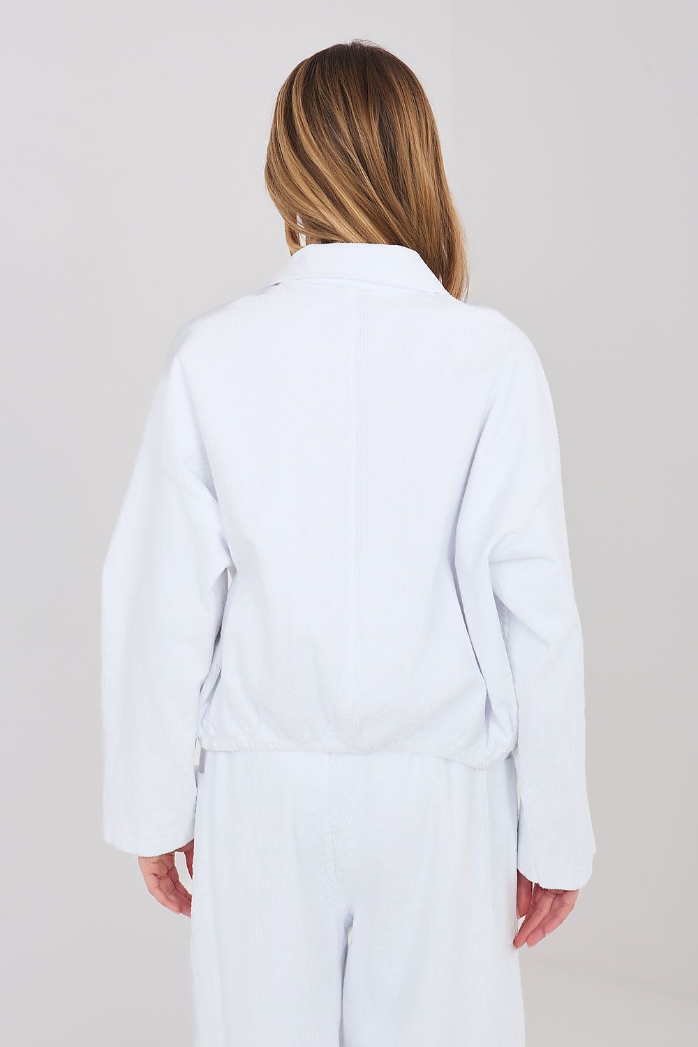 Person wearing a white coat against a plain background