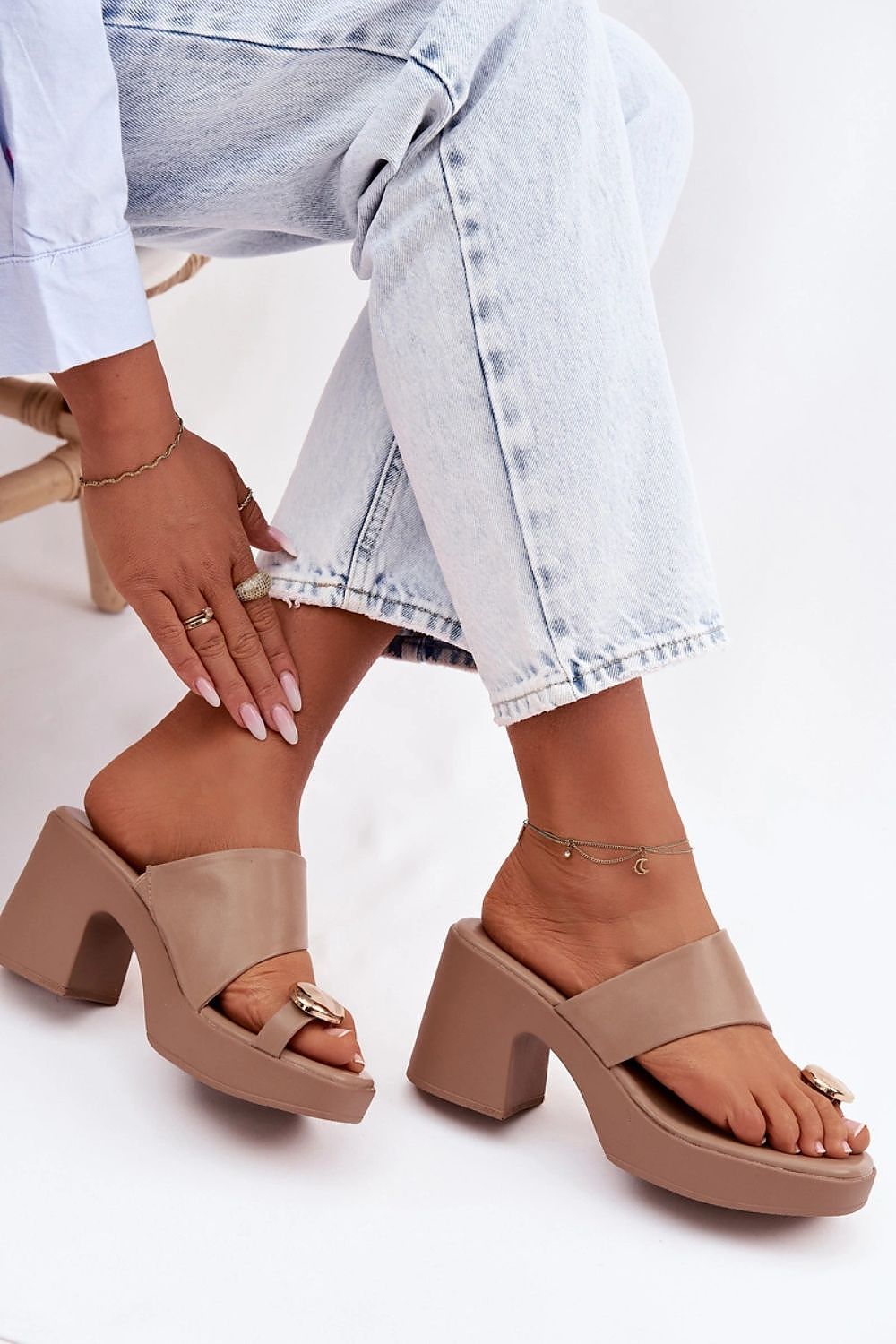 Beige sandals worn with light blue jeans on a white background
