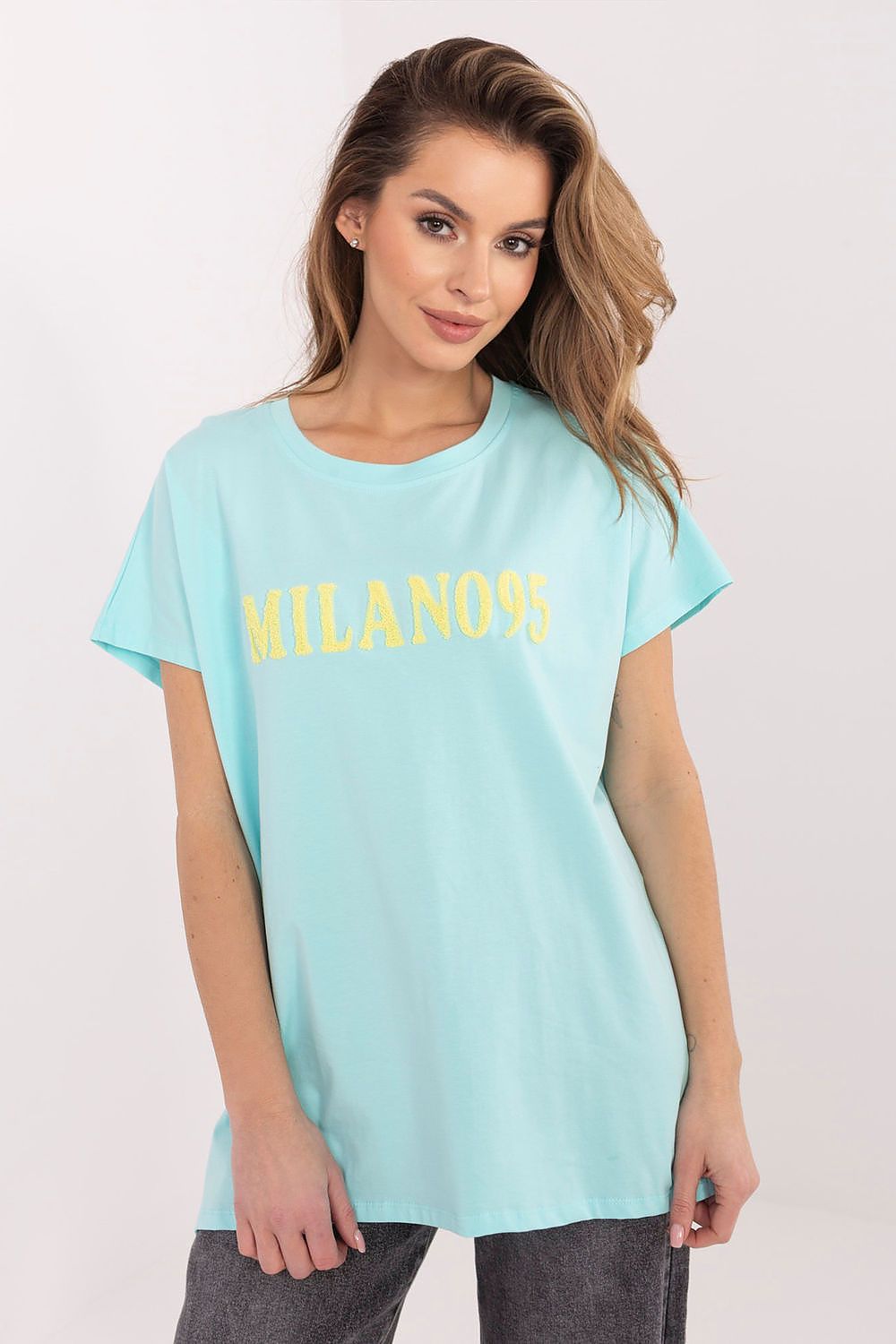 Woman wearing a light blue t-shirt with 'Milano' printed in yellow on a white background