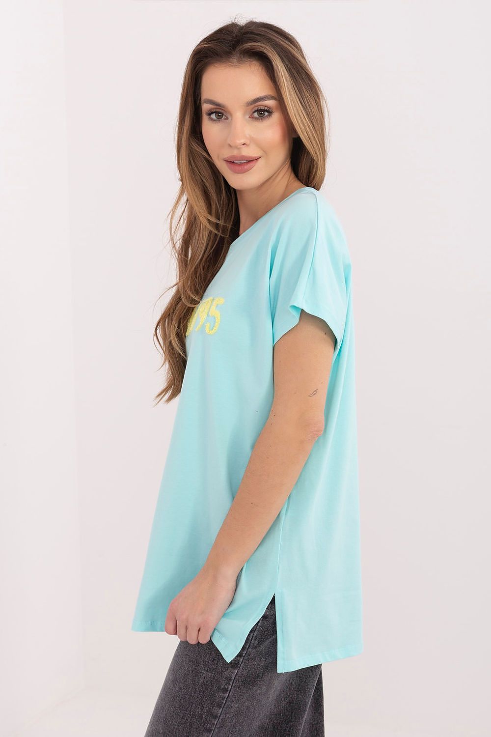 Woman wearing a light blue t-shirt with text on a plain background