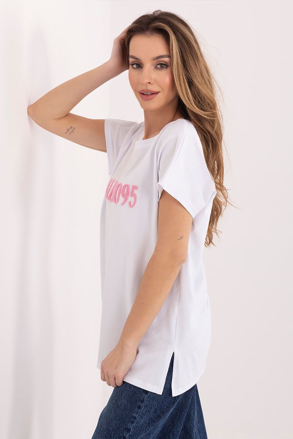 Woman wearing a white t-shirt with pink text on a plain background