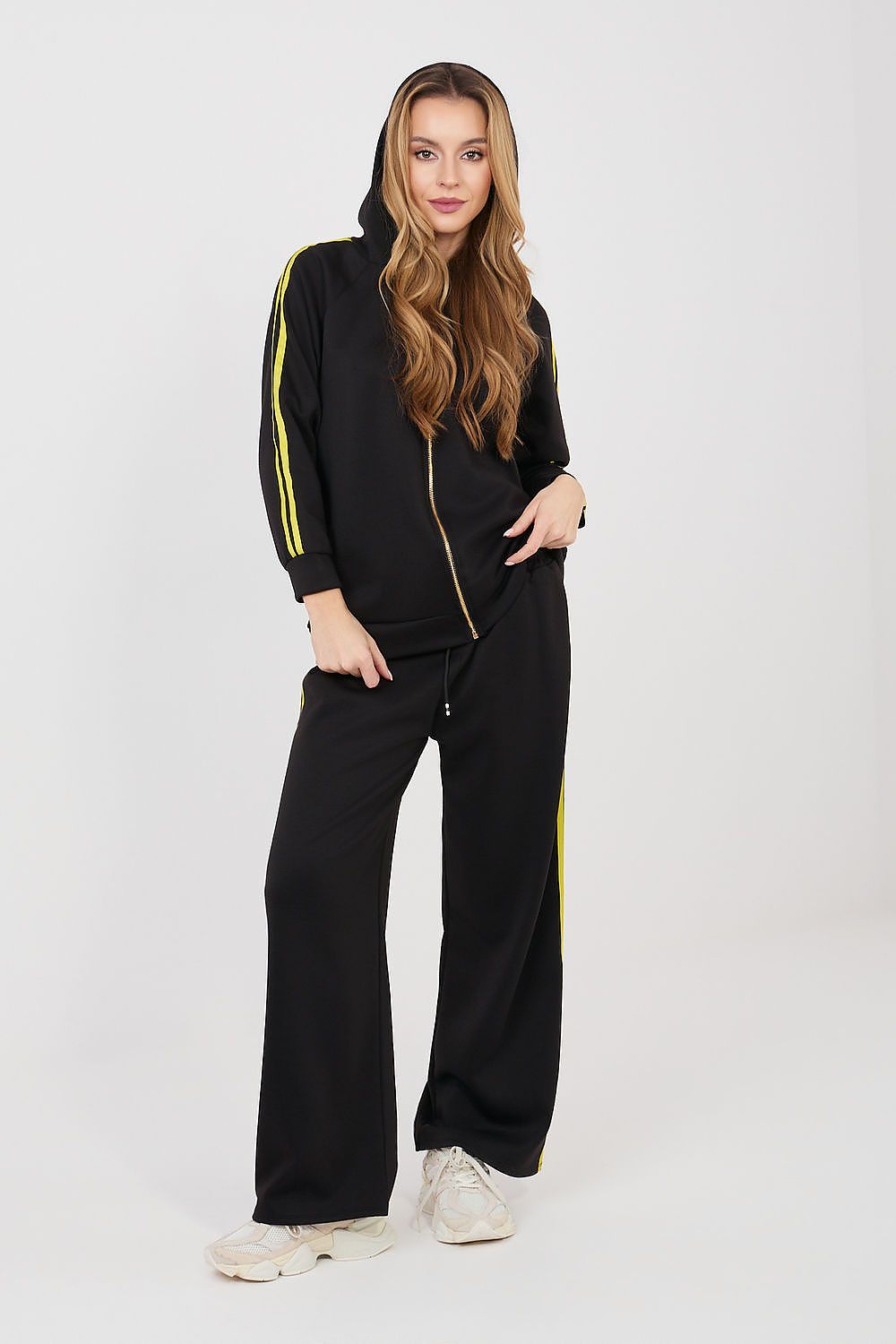 Woman wearing a black tracksuit with yellow stripes on a white background
