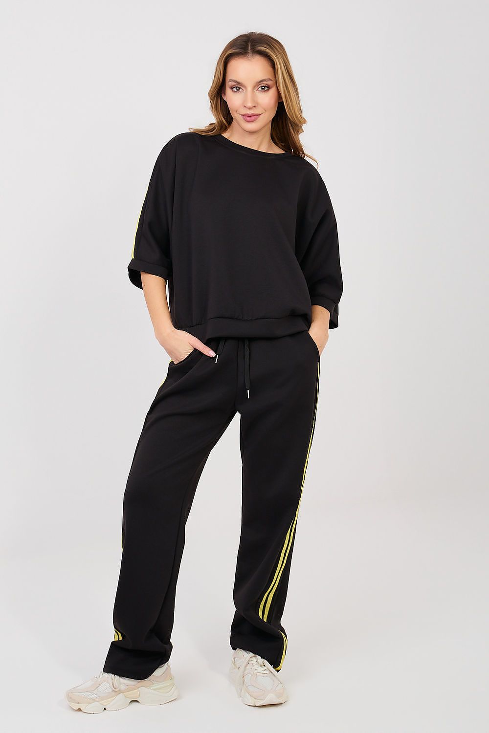 Woman wearing a black tracksuit with yellow stripes on a white background