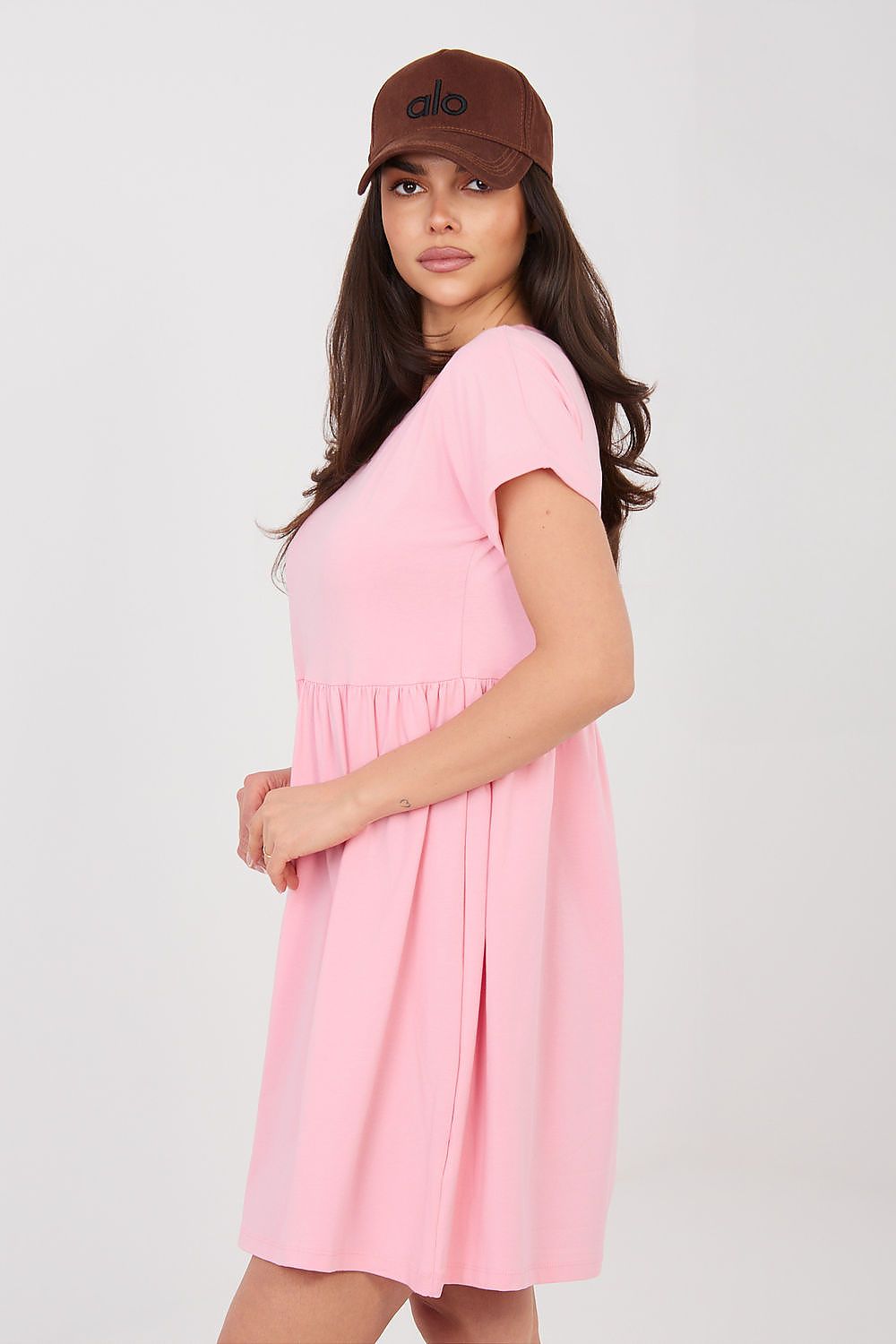Woman wearing a pink dress and brown cap on a white background