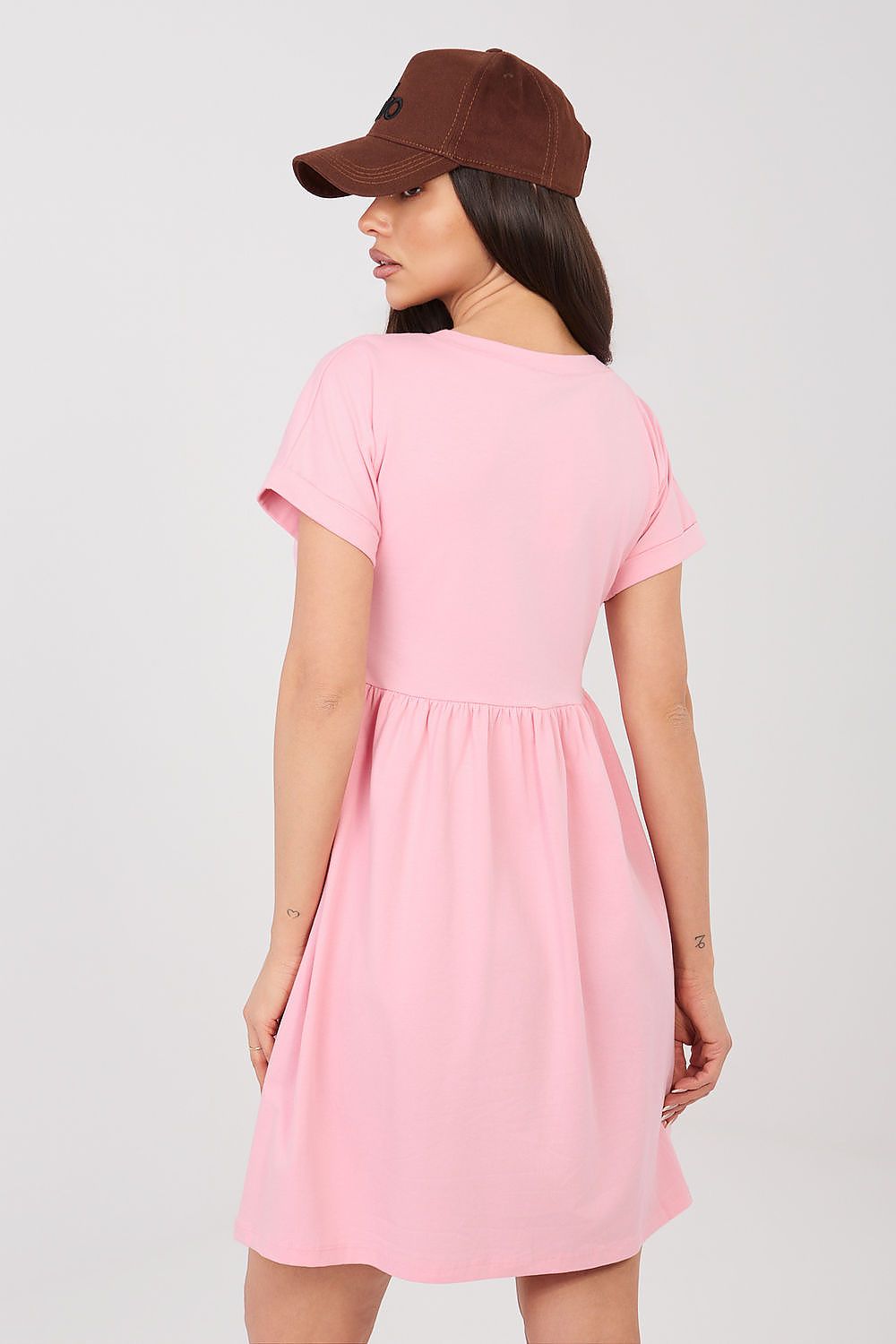 Woman wearing a pink dress and brown cap on a white background
