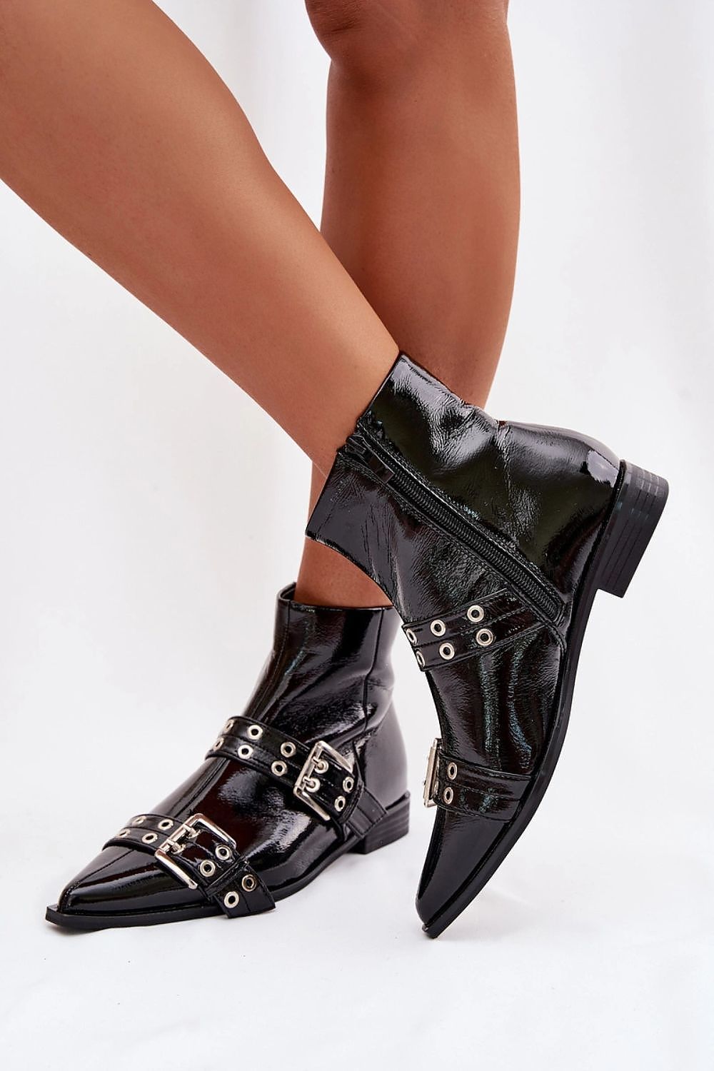 Black patent leather boots with metal buckles on a white background