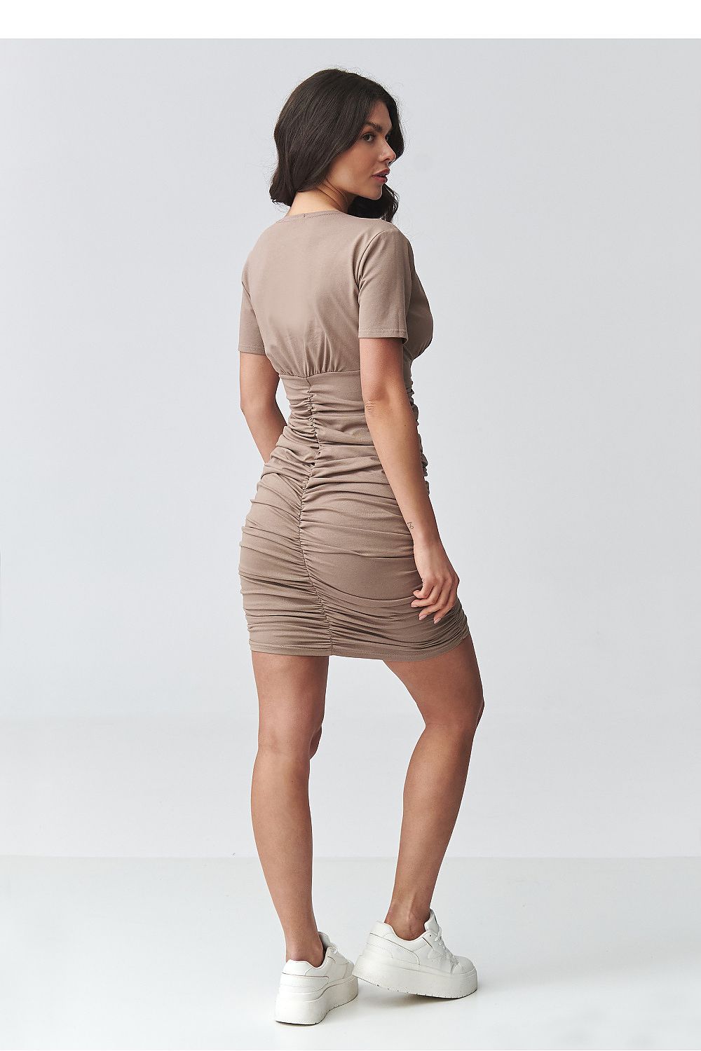 Woman wearing a beige dress on a white background