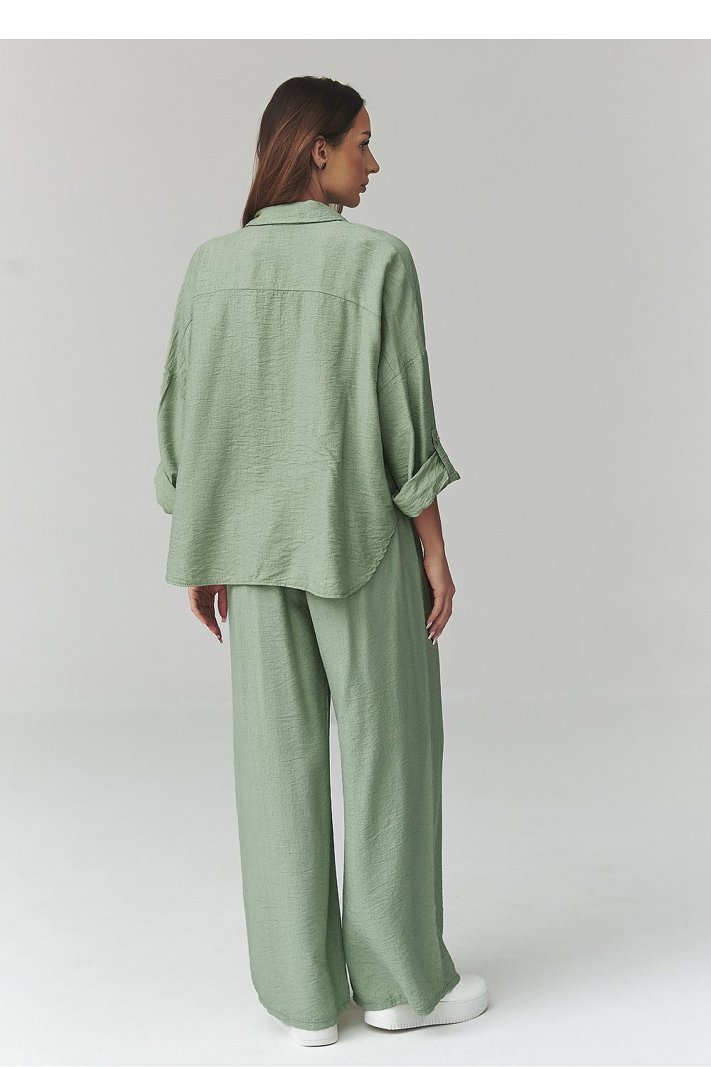 Woman wearing a green outfit on a plain background