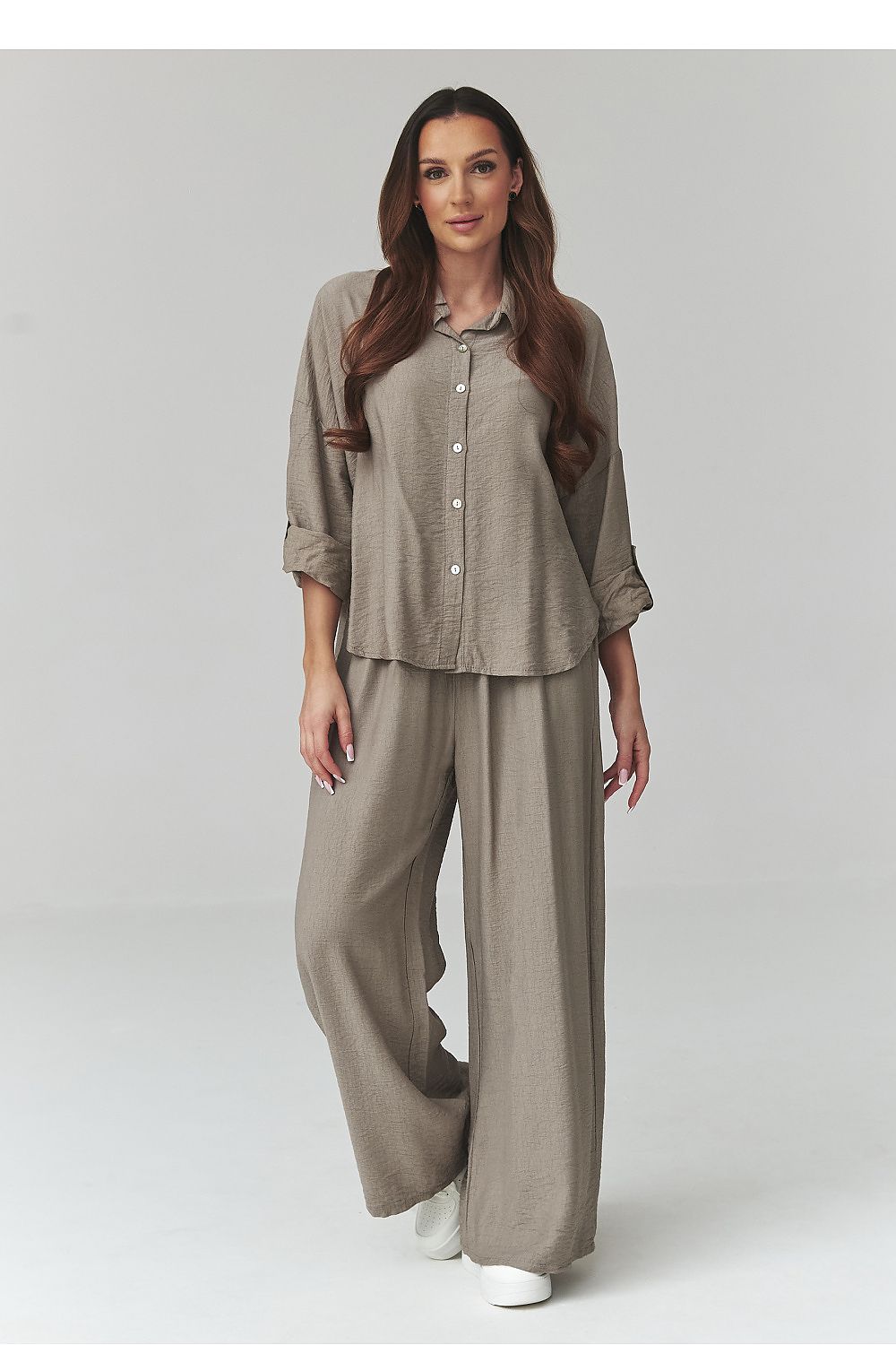 Woman wearing a beige shirt and pants set on a white background