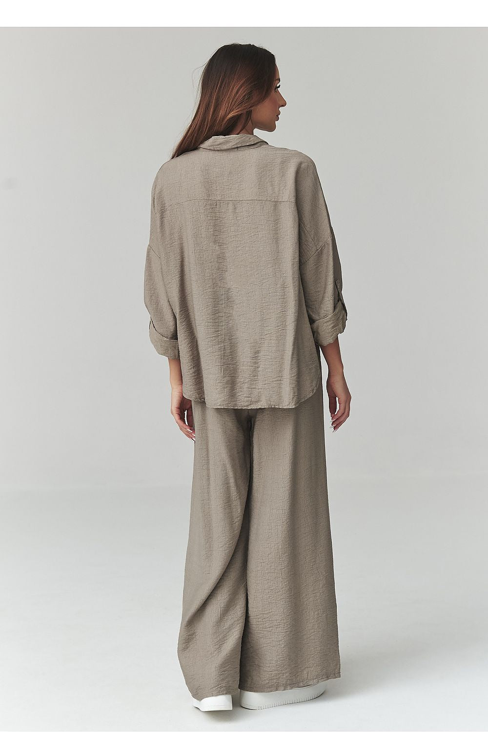 Woman wearing a beige outfit on a plain background