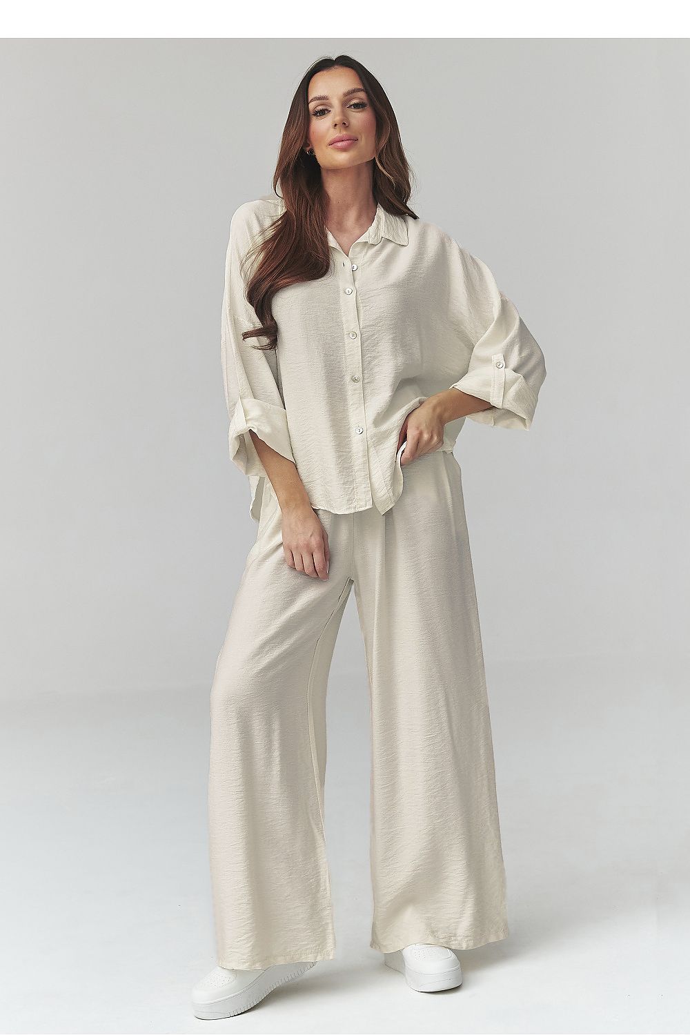Woman wearing a white outfit on a plain background
